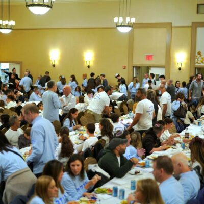 American (in blue shirts) and Israeli (in white) participants in Project 24's Thanks4Giving initiative, which brought hundreds of Israeli civilian defense teams to the U.S., eat a meal together at Congregation Rodeph Sholom in New York City on Nov. 12, 2024.